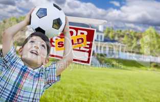 Boy Holding Ball In Front of House and Sold Sign