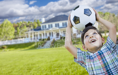 Smiling Young Boy Holding Soccer Ball In Front of House