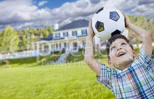 Smiling Young Boy Holding Soccer Ball In Front of House