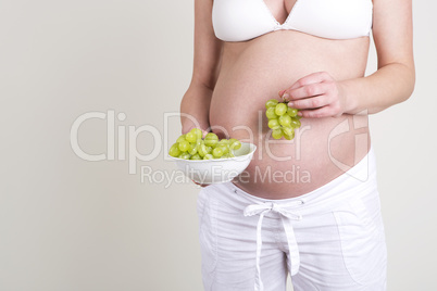 Pregnant woman with a bowl of grapes in her hands