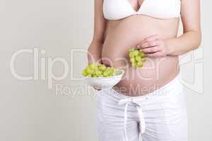Pregnant woman with a bowl of grapes in her hands