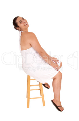 Woman in white dress sitting on chair.