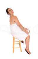 Woman in white dress sitting on chair.