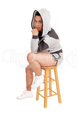 Girl sitting in hoodie on a chair.
