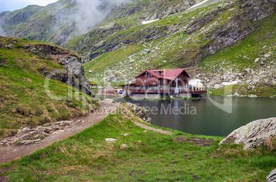 Idyllic view with typical lodge on Balea Lake shore in Fagaras M