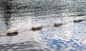 Four white floating marker buoys on water
