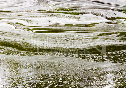 Abstract white foam swirls on green water