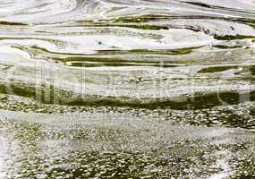 Abstract white foam swirls on green water