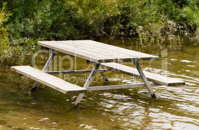 Empty picnic table in water by plants