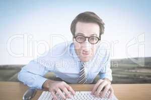Composite image of businessman typing on his keyboard wearing gl
