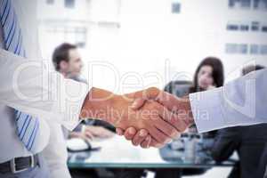 Composite image of close-up shot of a handshake in office