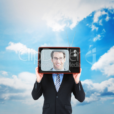Composite image of businessman hiding head with a box