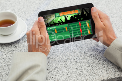 Composite image of businessman holding small tablet at table