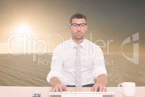 Composite image of businessman working at his desk