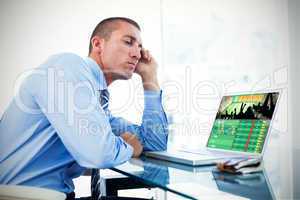 Composite image of tired businessman looking at his laptop