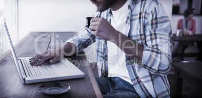 Casual man using laptop drinking espresso