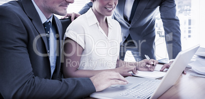 Young colleagues using laptop at office desk