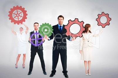 Composite image of business people holding cogs