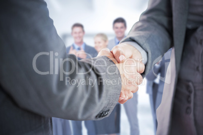 Composite image of business people shaking hands close up