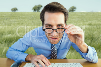 Composite image of focused businessman holding his glasses