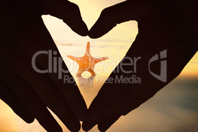 Composite image of woman making heart shape with hands