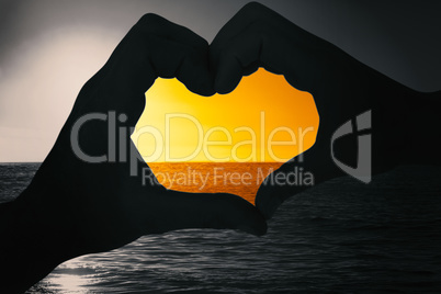 Composite image of couple making heart shape with hands