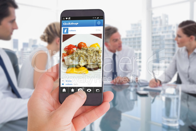 Composite image of female hand holding a smartphone