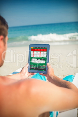 Composite image of man using digital tablet on deck chair at the