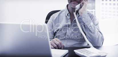 Businessman on call in front of laptop at office desk