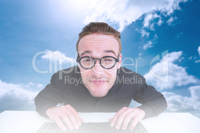 Composite image of smiling businessman typing on keyboard at des