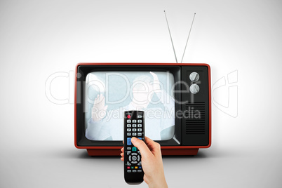 Composite image of hand holding remote control