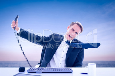 Composite image of businessman shouting as he holds out phone