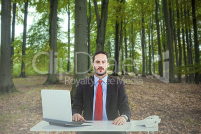 Composite image of unsmiling businessman sitting at desk