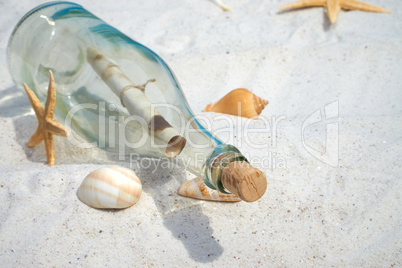 Flaschenpost und Muscheln liegen auf dem Sandstrand