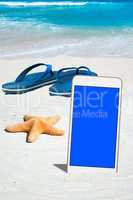 Smartphone, Flip Flops und Seestern am Strand