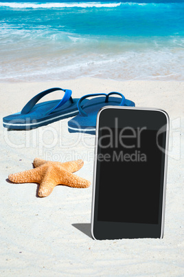 Smartphone, Flip Flops und Seestern am Strand