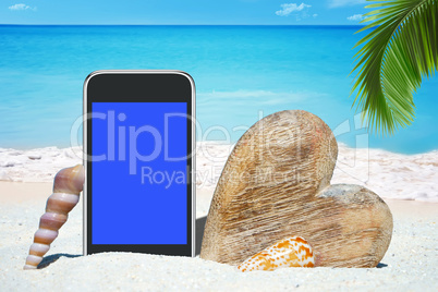 Smartphone, Herz aus Holz und Muscheln am Strand