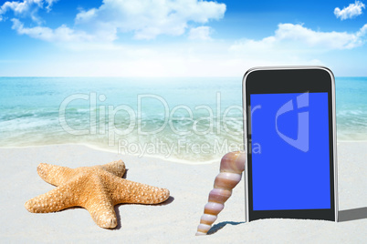 Schwarzes Smartphone und Muscheln am Sandstrand