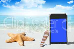 Schwarzes Smartphone und Muscheln am Sandstrand