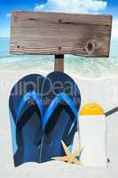 Flip Flops, Sonnenmilch und leeres Holzschild am Strand