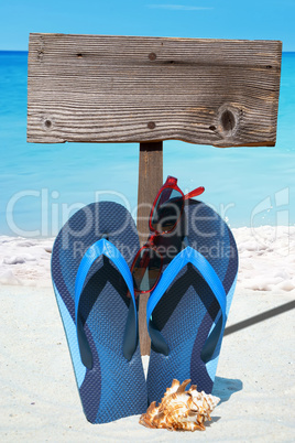 Flip Flops, Sonnenbrille und leeres Holzschild am Strand