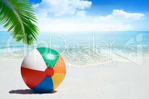 Bunter Wasserball unter Palmwedel am Strand