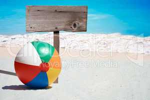 Bunter Wasserball und leeres Holzschild am Strand
