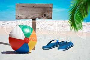 Bunter Wasserball, Flip Flops und leeres Holzschild am Strand