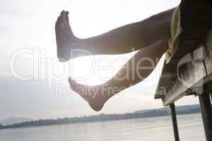 Man on a dock holding his feet in the air