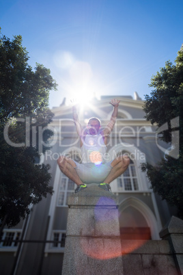 Extreme athlete crouching on pillar and holding arms up in the a