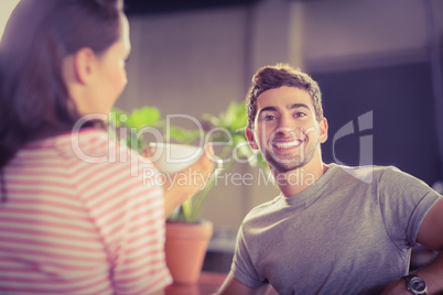 Smiling young man having coffee with his friend