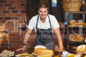 Handsome waiter bended over a food table