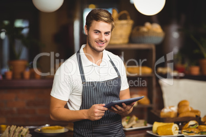 Handsome waiter holding a tablet