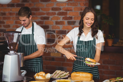 Pretty waitress picking a sandwich